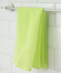 Green towel hanging on a silver rack against a white tiled wall