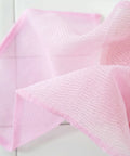 Close-up of pink textured cloths on a light wooden surface