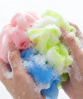 Colorful washcloths with suds held by hands against a white background