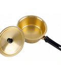 Gold-colored pot and lid with a black handle on a white background
