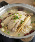 Chicken soup with herbs and vegetables in a pot on a stove