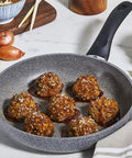 Frying pan with meatballs on a marble countertop