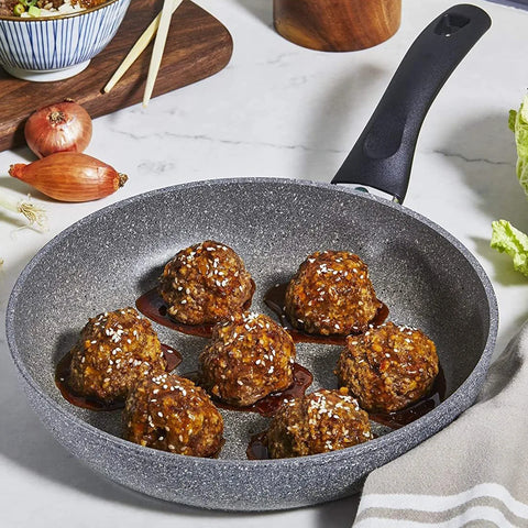 Frying pan with meatballs on a marble countertop