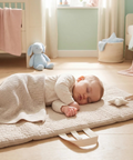 Baby lying on a mat in a nursery with toys around
