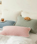 Set of green, blue, and pink pillows on a white bed