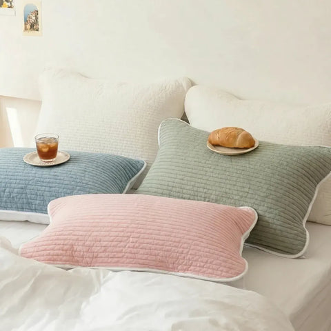 Set of green, blue, and pink pillows on a white bed