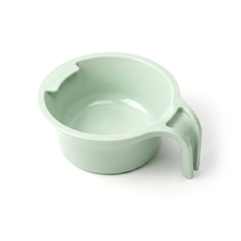 Light green plastic spoon holder cup with a handle on a white background