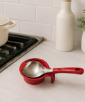 Red ladle holder with a silver ladle on a kitchen counter