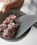 Gray spoon scooping rice from a bowl with a blurred background