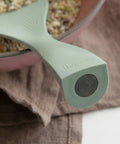 Close-up of a green rice spatula with 'Bogen' branding, held over a container of food.