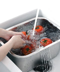 Tomatoes being washed in a small dish tub with running water