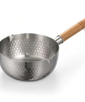 A stainless steel saucepan with a hammered hexagonal pattern exterior and a light brown wooden handle, shown on a white background.