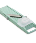Mint green vegetable mandoline slicer on a white background