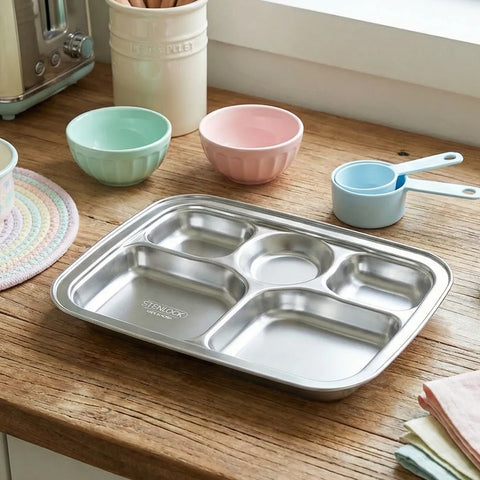 Stainless steel divided tray on a wooden table with colorful bowls and measuring cups in the background.