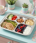 Metallic lunch tray with compartments filled with a variety of food items on a light blue countertop.