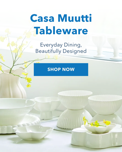 A styled dining table display featuring Casa Muutti tableware in white ceramic, including plates, bowls, and small dishes, with pink and gray placemats. The right side has a white background with the text 'Casa Muutti Tableware', a blue 'SHOP NOW' button, and the Casa Muutti logo.