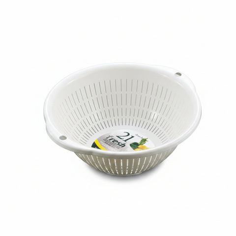 A white plastic colander basket with vertical slits and a small handle, shown on a neutral gray background. A circular paper label is visible inside the basket.