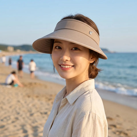 Woman wearing a beige visor on a beach with ocean and sky in the background