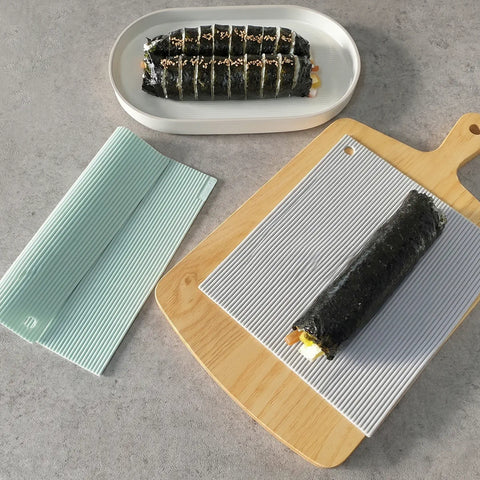 Sushi rolls on a textured white mat and wooden cutting board with a gray background