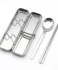 Stainless steel lunch box with spoon and chopsticks on a white background