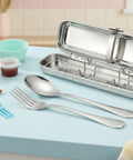 Stainless steel cutlery set with a carrying case on a light blue surface.