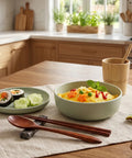 Dish of food on a table with chopsticks and a cup in a kitchen setting