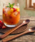Glass of iced fruit tea with wooden spoons on a wooden table