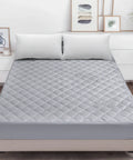 Gray mattress cover on a bed in a bedroom setting with decor elements.