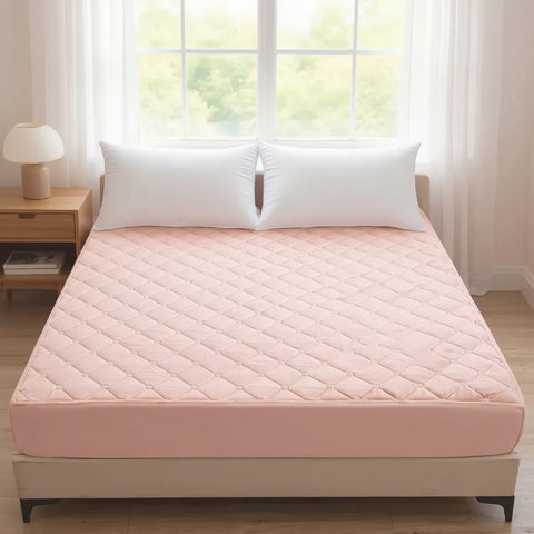 Pink mattress cover on a bed with white pillows in a bright room.