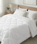 White comforter and pillows on a bed in a bedroom setting
