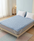 Bed with a blue mattress cover and white pillows in a bedroom setting.