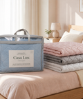 Folded Mattress Pads stacked on a bed next to a 'Casa Lux' packaging box.
