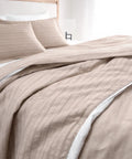 Beige striped bedding set on a bed with white pillows.