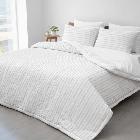 White textured comforter on a bed with pillows in a bright room.
