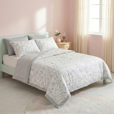 Bedroom with a bed featuring a floral comforter and pillows, a nightstand with a lamp and vase.