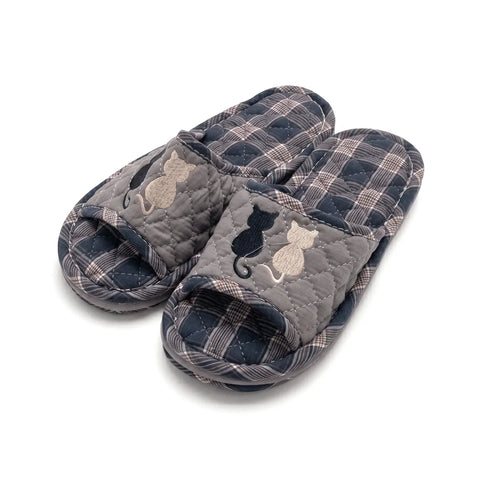 Pair of plaid slippers with cat designs on a white background