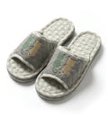 Pair of gray ad\nd green slippers with cat designs on a white background
