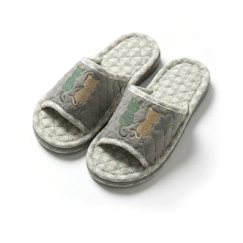 Pair of gray ad\nd green slippers with cat designs on a white background