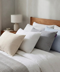 Bed with decorative pillows and a lamp on a nightstand in a bedroom setting.
