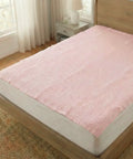 Pink mattress cover on a bed in a bedroom with wooden headboard and nightstand.