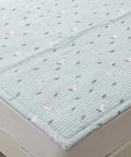 Quilted mattress cover with bird pattern on a bed