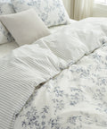 Floral and striped bedding set on a bed with pillows.