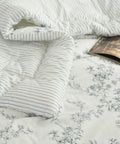 Floral patterned bedding with a striped comforter on top