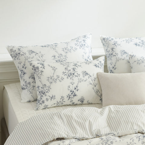 Floral patterned pillows on a bed with a neutral background