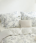 Floral and striped bedding set on a bed with white walls.
