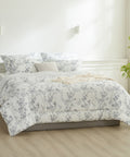 Floral patterned comforter set on a bed in a bright bedroom with light wood flooring.