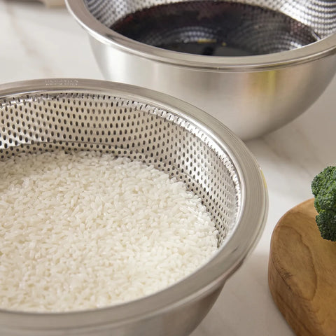 Metal colander with white rice and a piece of broccoli on a light surface