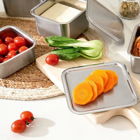 Stainless steel containers with sliced carrots and vegetables on a kitchen counter