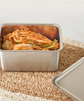Stainless steel container with kimchi on a woven mat