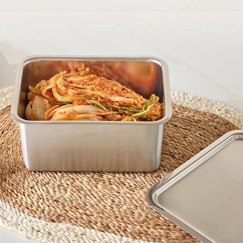 Stainless steel container with kimchi on a woven mat
